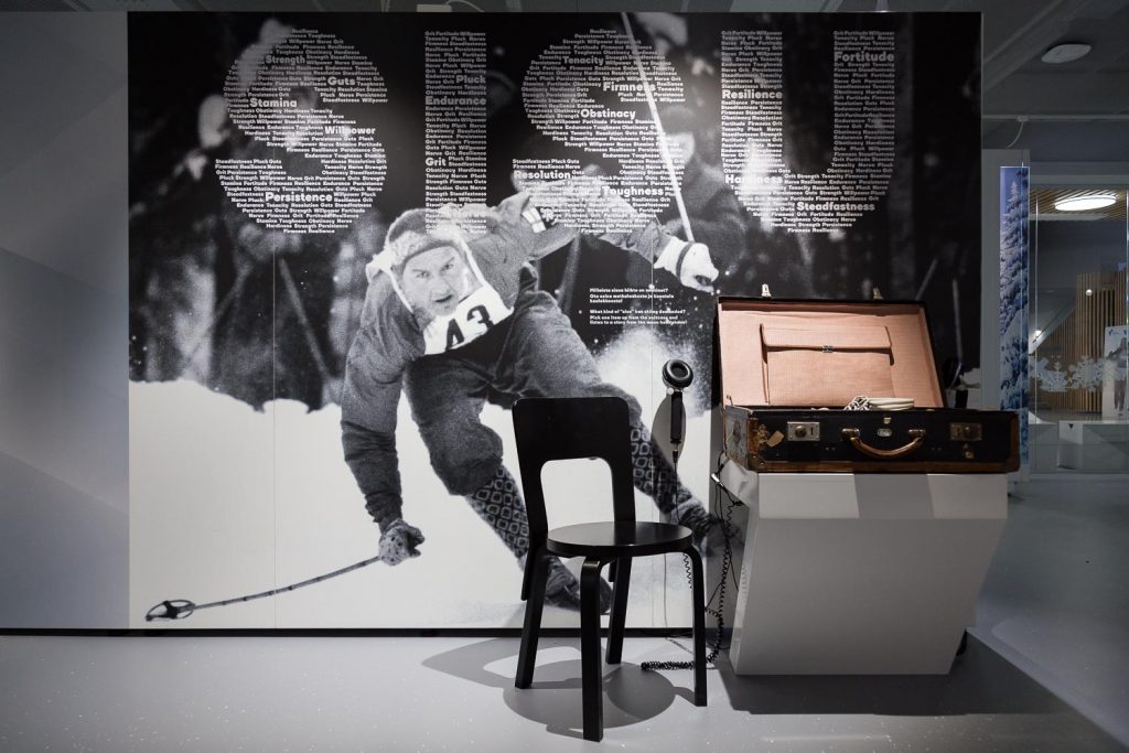 Suuri printti Veikko Hakulisesta, hiihtäjästä ja kuuntelulaukku, josta voi kuunnella hiihtäjien tarinoita